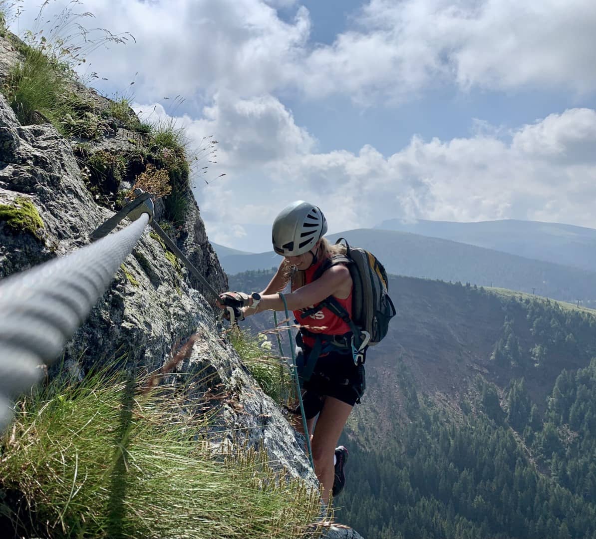 Eine Frau auf einem Klettersteig in Südtirol mit Weitblick in die Berge